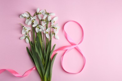 Beautiful snowdrops and number 8 made of ribbon on pink background, flat lay