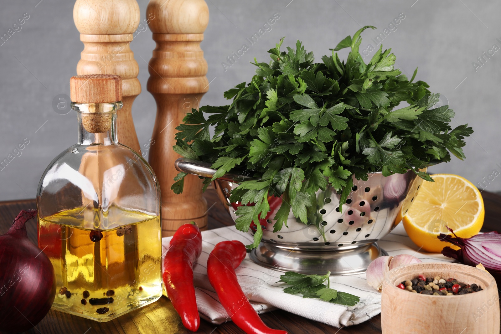 Photo of Colander with fresh parsley, spices and other products on wooden table