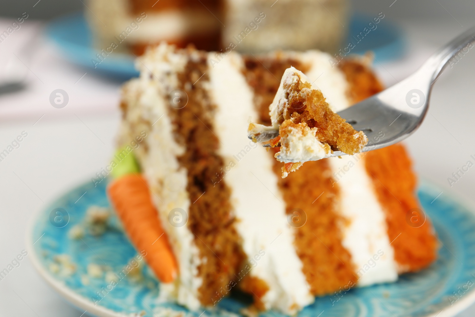 Photo of Fork with piece of carrot cake against blurred dessert, closeup. Space for text