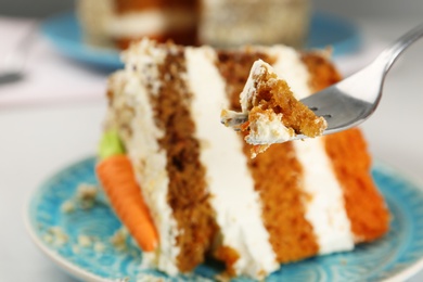 Fork with piece of carrot cake against blurred dessert, closeup. Space for text