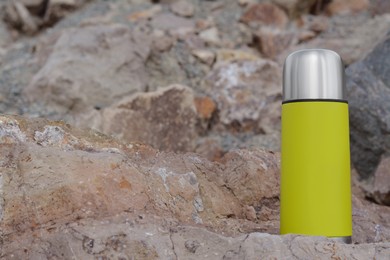 Metallic thermos with hot drink on stone outdoors, space for text