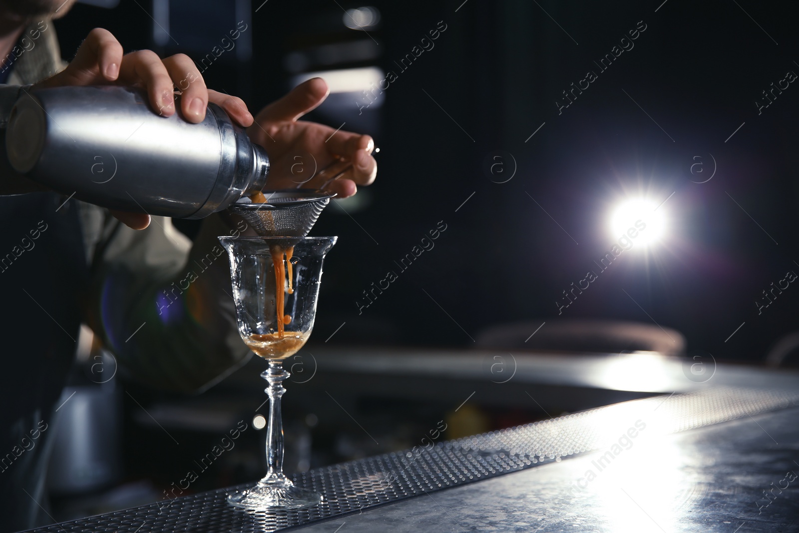 Photo of Barman pouring martini espresso cocktail into glass at counter, closeup. Space for text