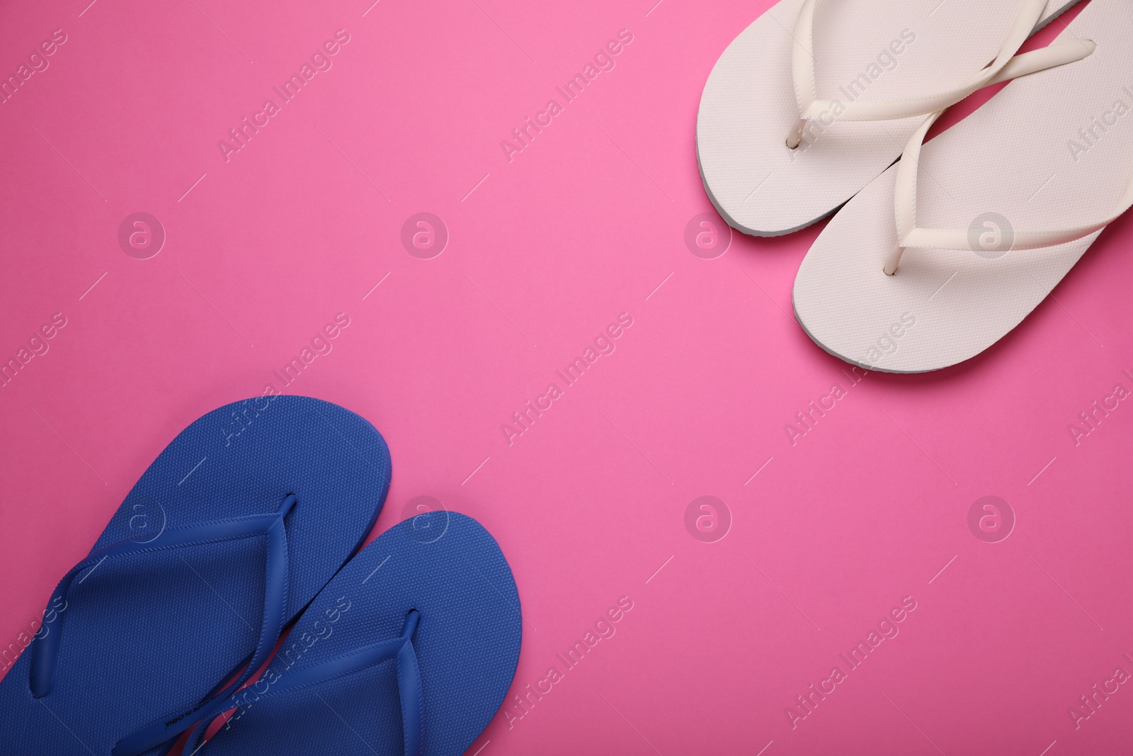 Photo of Stylish white and blue flip flops on pink background, flat lay. Space for text