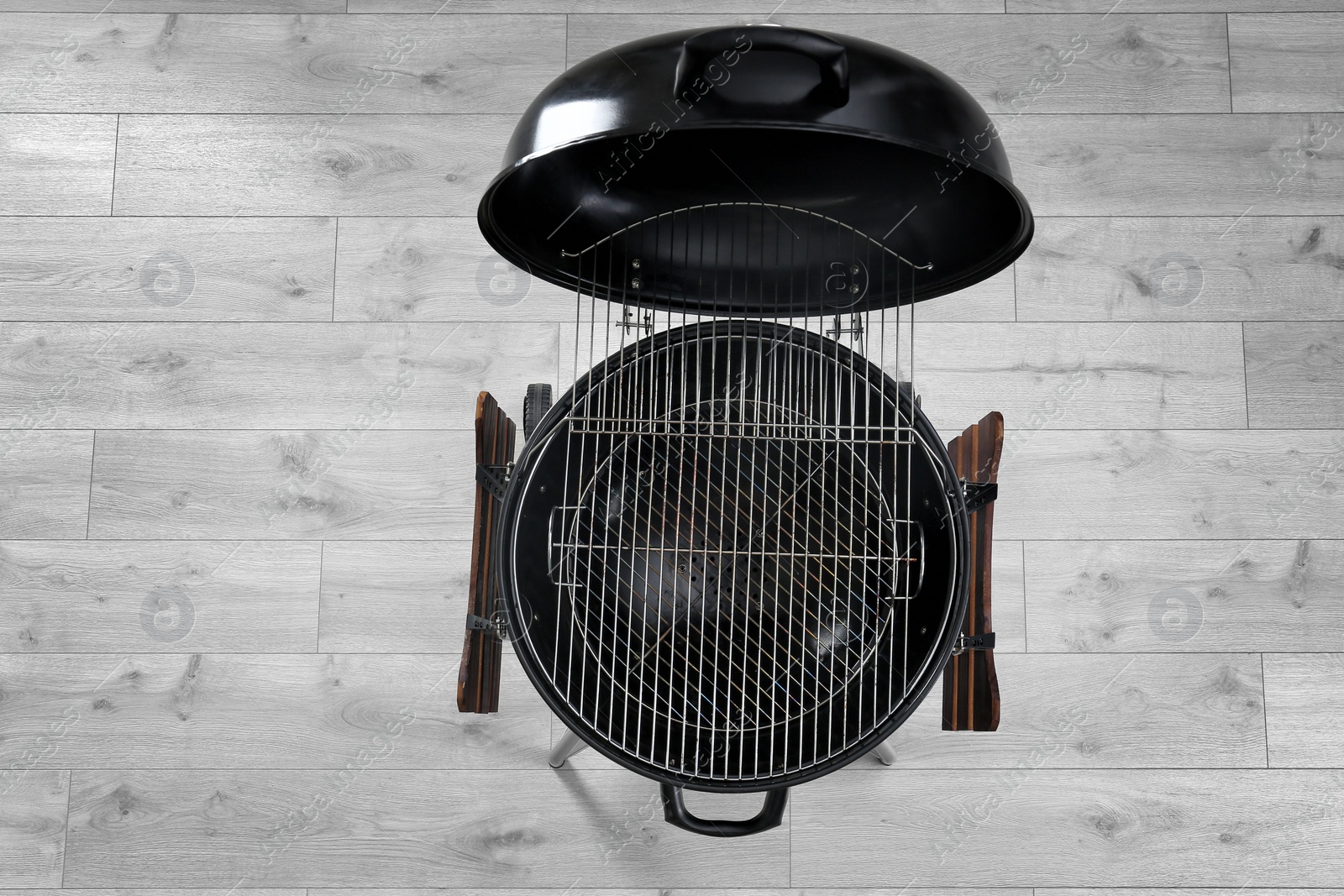 Photo of New modern barbecue grill on wooden floor