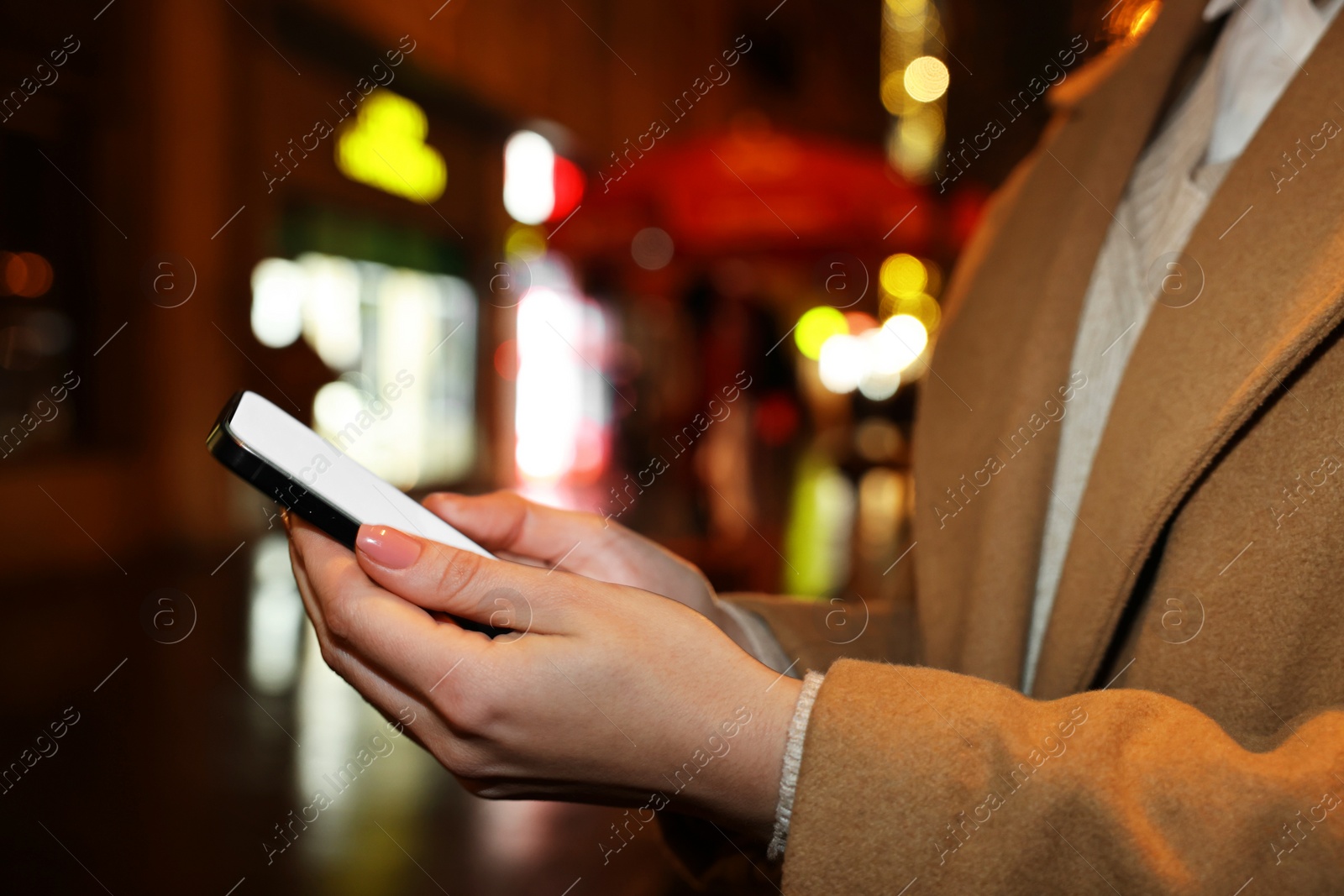 Photo of Woman with smartphone on night city street, closeup