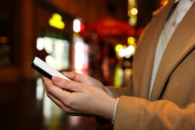 Woman with smartphone on night city street, closeup