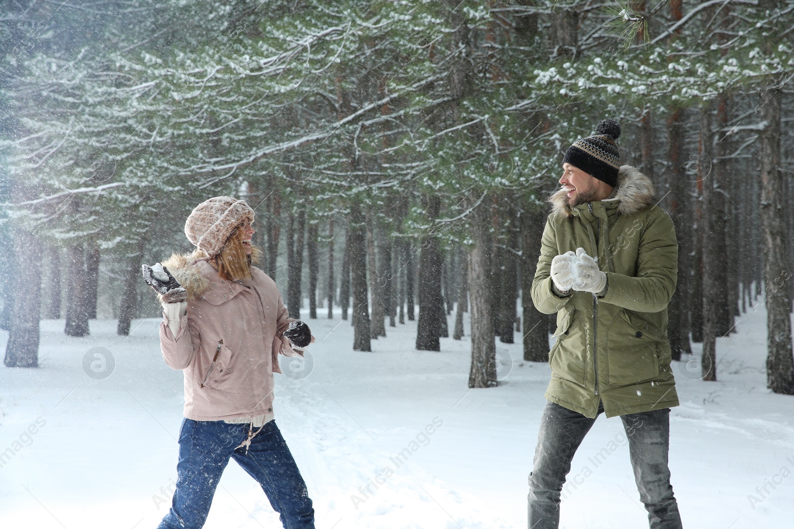 Photo of Happy couple playing snowballs in winter forest