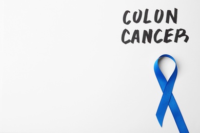 Blue awareness ribbon and words COLON CANCER on white background, top view