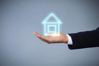 Mortgage rate. Man holding illustration of house on grey background, closeup. Space for text