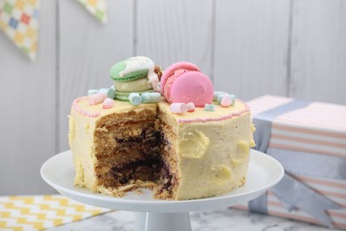 Delicious cake decorated with macarons and marshmallows on table, closeup view