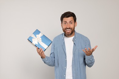Photo of Emotional man holding gift box on light grey background