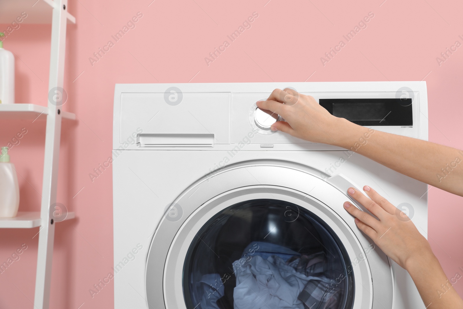 Photo of Woman putting laundry into washing machine indoors, closeup
