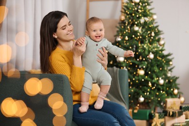 Photo of Happy young mother with her cute baby in room decorated for Christmas. Winter holiday