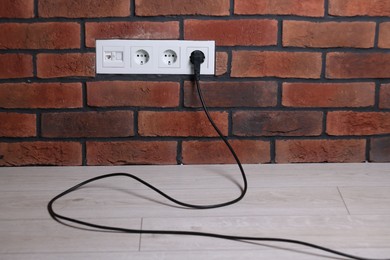 Photo of Power sockets and electric plug on brick wall