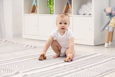 Children toys. Cute little boy playing with wooden cars on rug at home