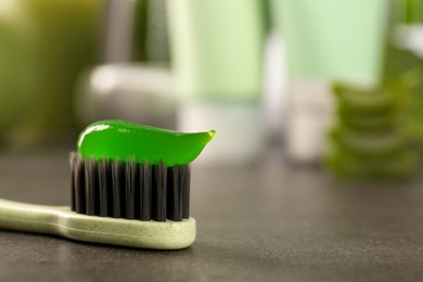 Photo of Brush with aloe vera toothpaste on grey table, closeup. Space for text