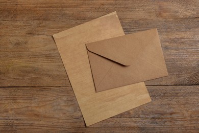 Photo of Envelope and sheet of parchment paper on wooden table, flat lay