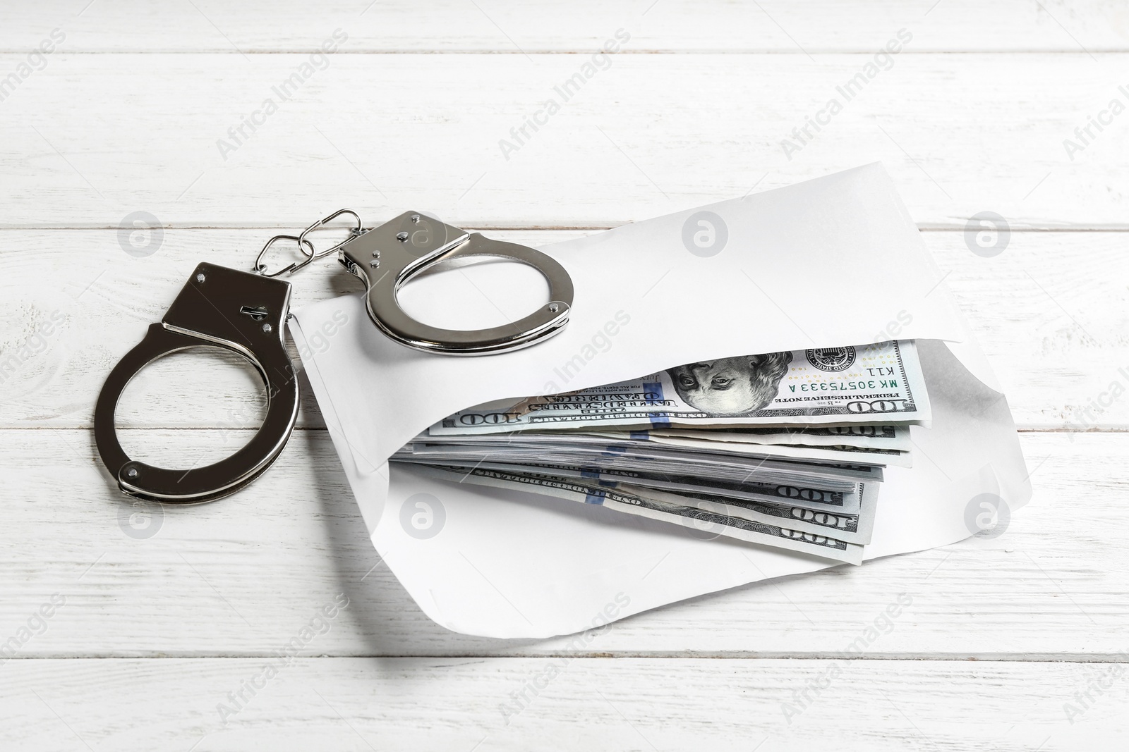 Photo of Dollar bills and handcuffs on white wooden table. Bribe concept