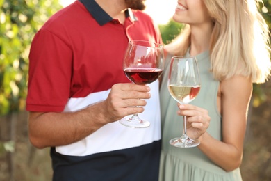 Young couple holding glasses of wine at vineyard