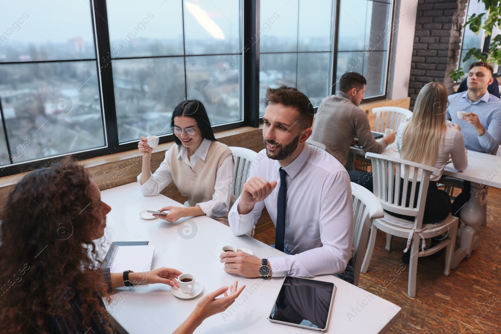 Photo of Coworkers having coffee break near window in cafe