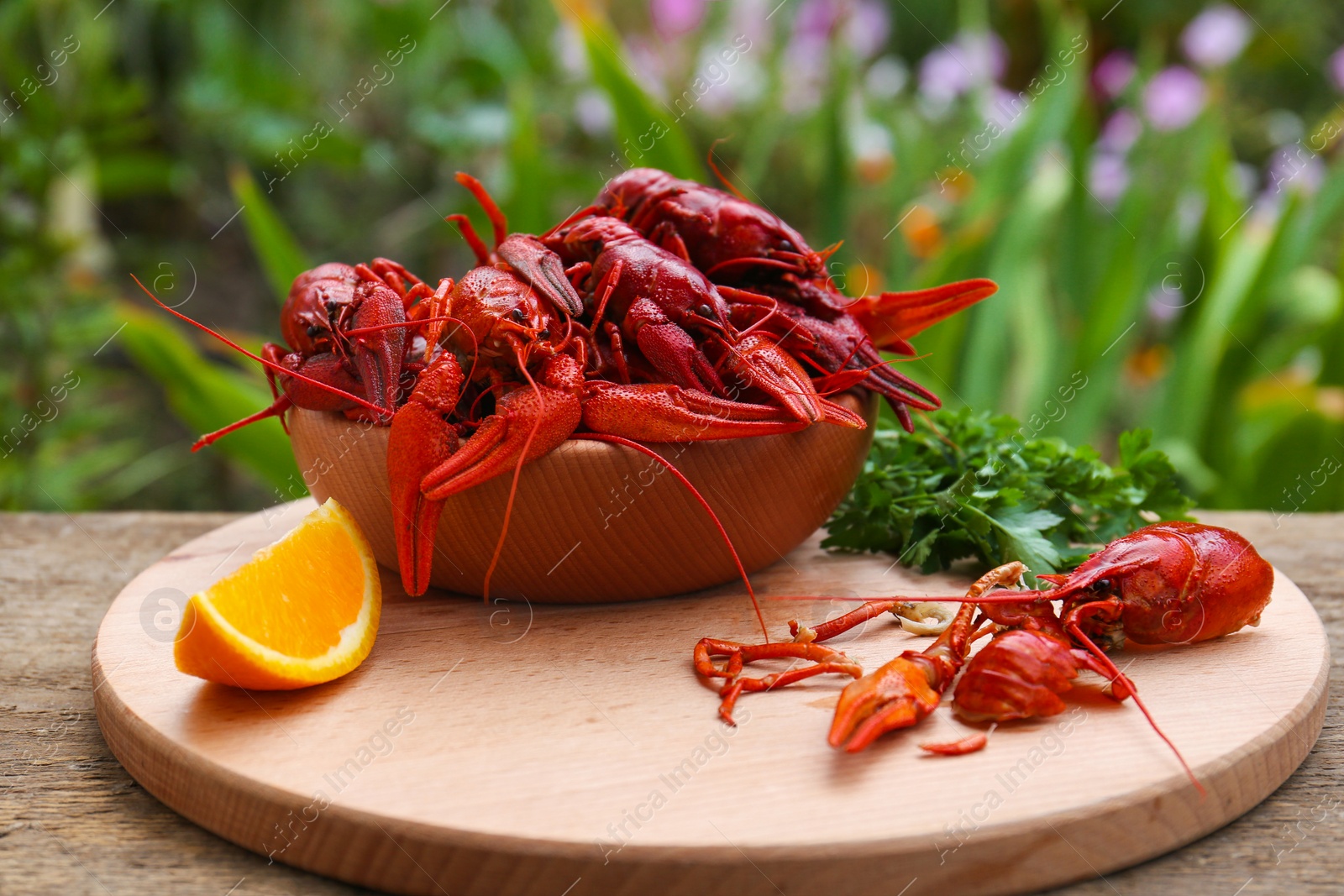 Photo of Delicious red boiled crayfish and orange on wooden table