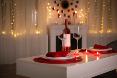 Photo of Romantic table setting with wine and candles for Valentine's day dinner indoors