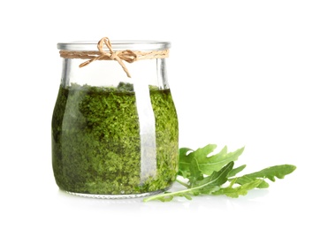 Photo of Jar of tasty pesto and arugula on white background