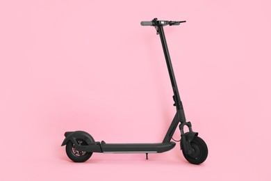 Photo of Modern electric kick scooter on pink background