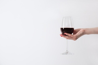 Woman holding glass of red wine on white background