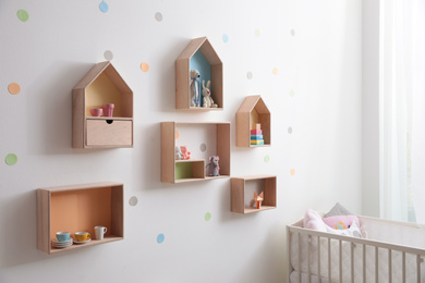 Photo of Stylish baby room interior design with house shaped shelves and crib