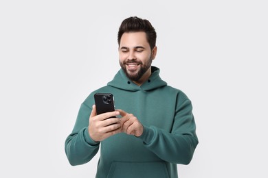 Happy young man using smartphone on white background