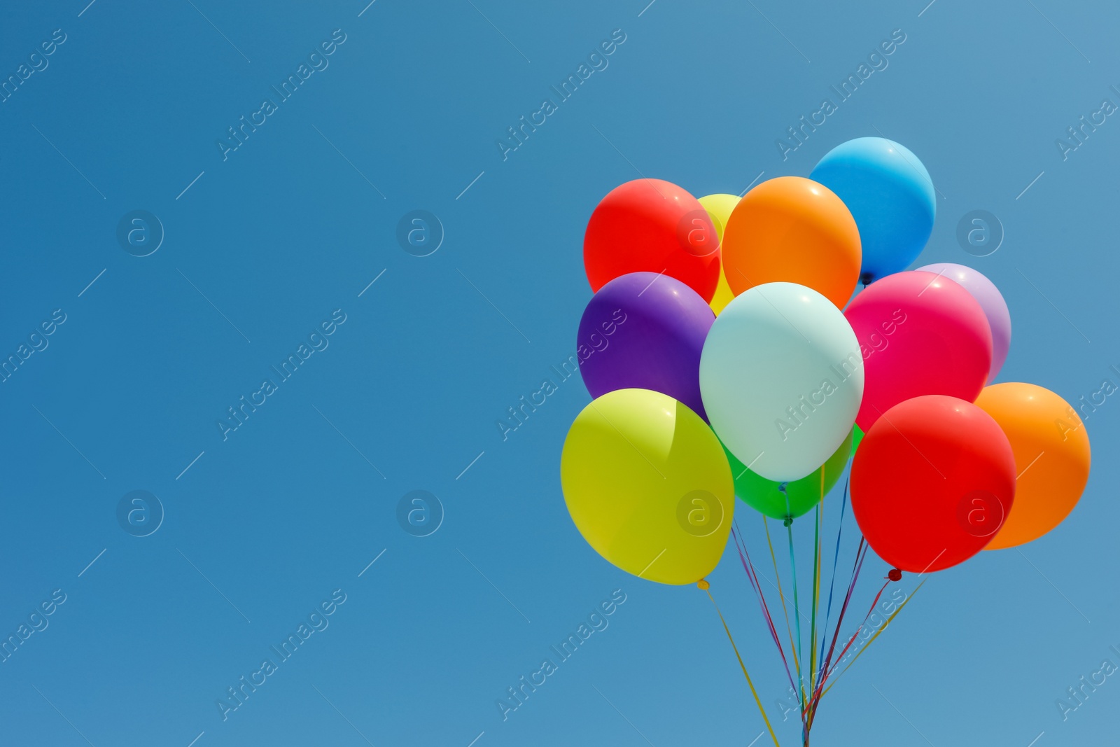Photo of Bunch of colorful balloons against blue sky. Space for text