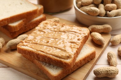 Photo of Delicious toasts with peanut butter and nuts on light wooden table, closeup