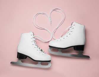 Photo of Pair of white ice skates on pink background, top view