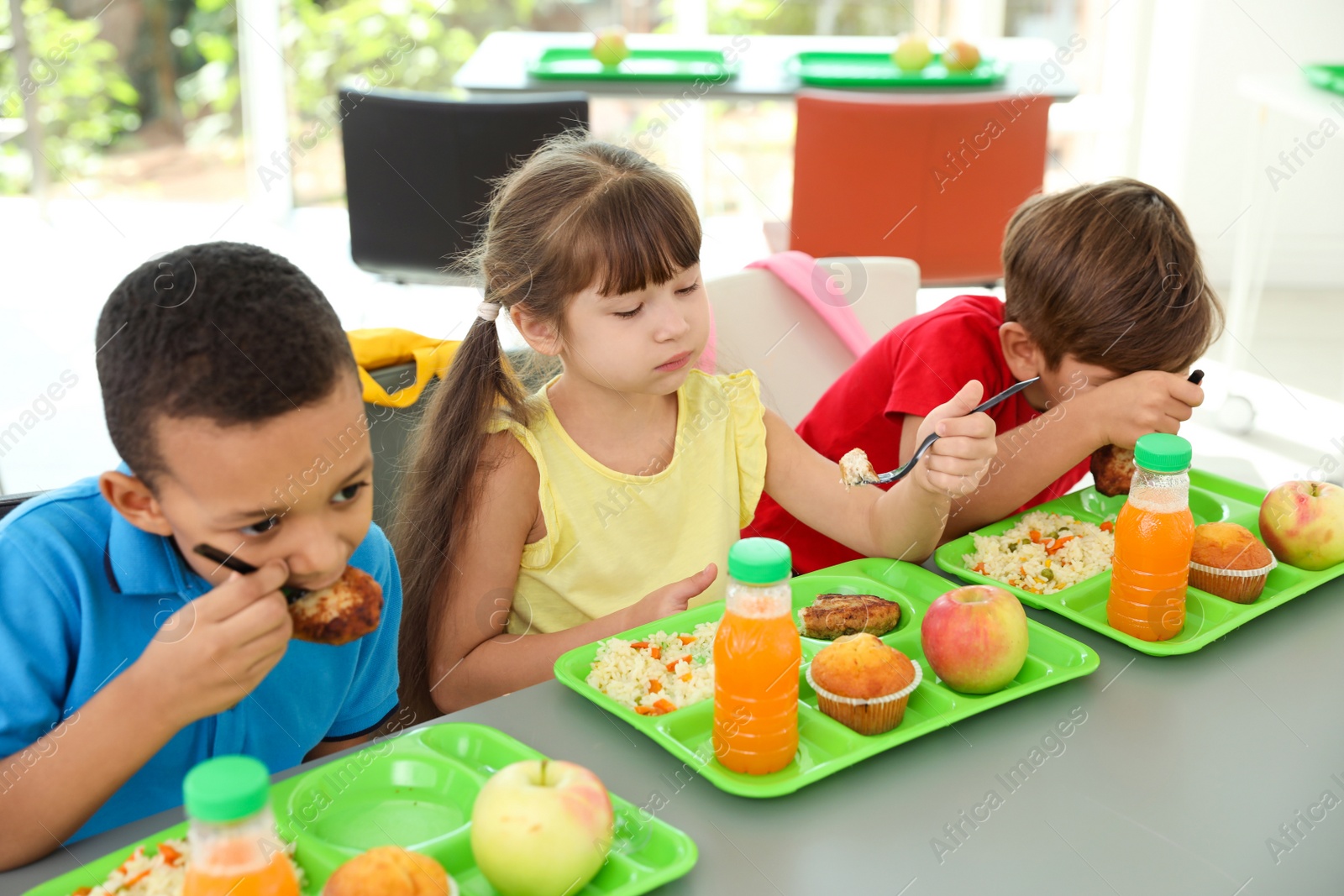 Photo of Children sitting at table and eating healthy food during break at school