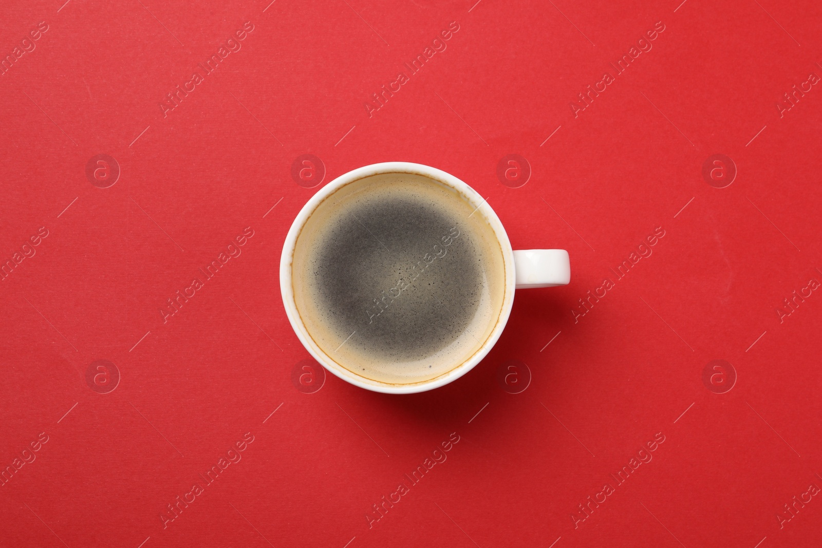 Photo of Aromatic coffee in cup on red background, top view