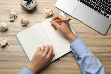 Woman working at table with crumpled paper, top view. Generating idea