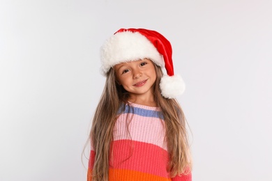 Photo of Happy little child in Santa hat on light grey background. Christmas celebration