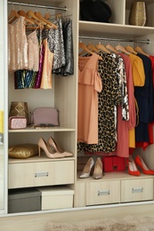 Photo of Different stylish women's clothes on hangers in wardrobe