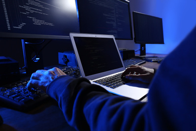 Photo of Hacker with computers in dark room, closeup. Cyber crime