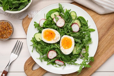 Photo of Delicious salad with boiled egg, vegetables and arugula served on white wooden table, flat lay