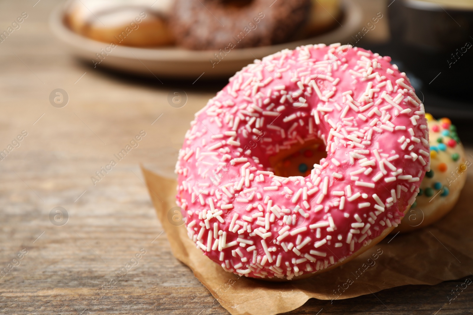 Photo of Delicious glazed donuts on wooden table, closeup. Space for text