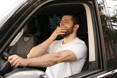 Tired man yawning while driving his modern car