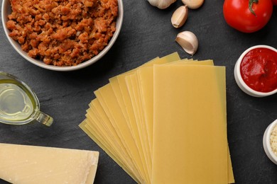 Photo of Flat lay composition with products for cooking lasagna on dark textured table