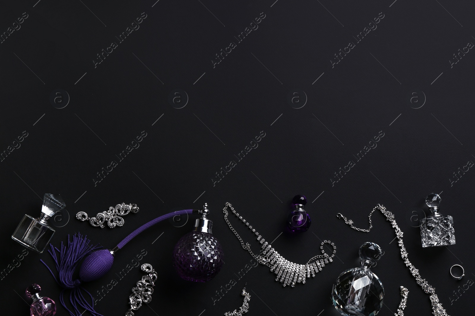 Photo of Composition with perfume bottles and jewellery on black background, flat lay. Space for text