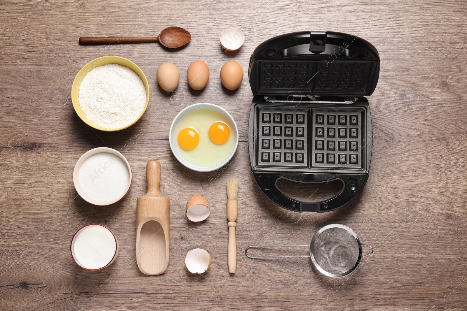 Photo of Flat lay composition with ingredients and Belgian waffle maker on wooden table