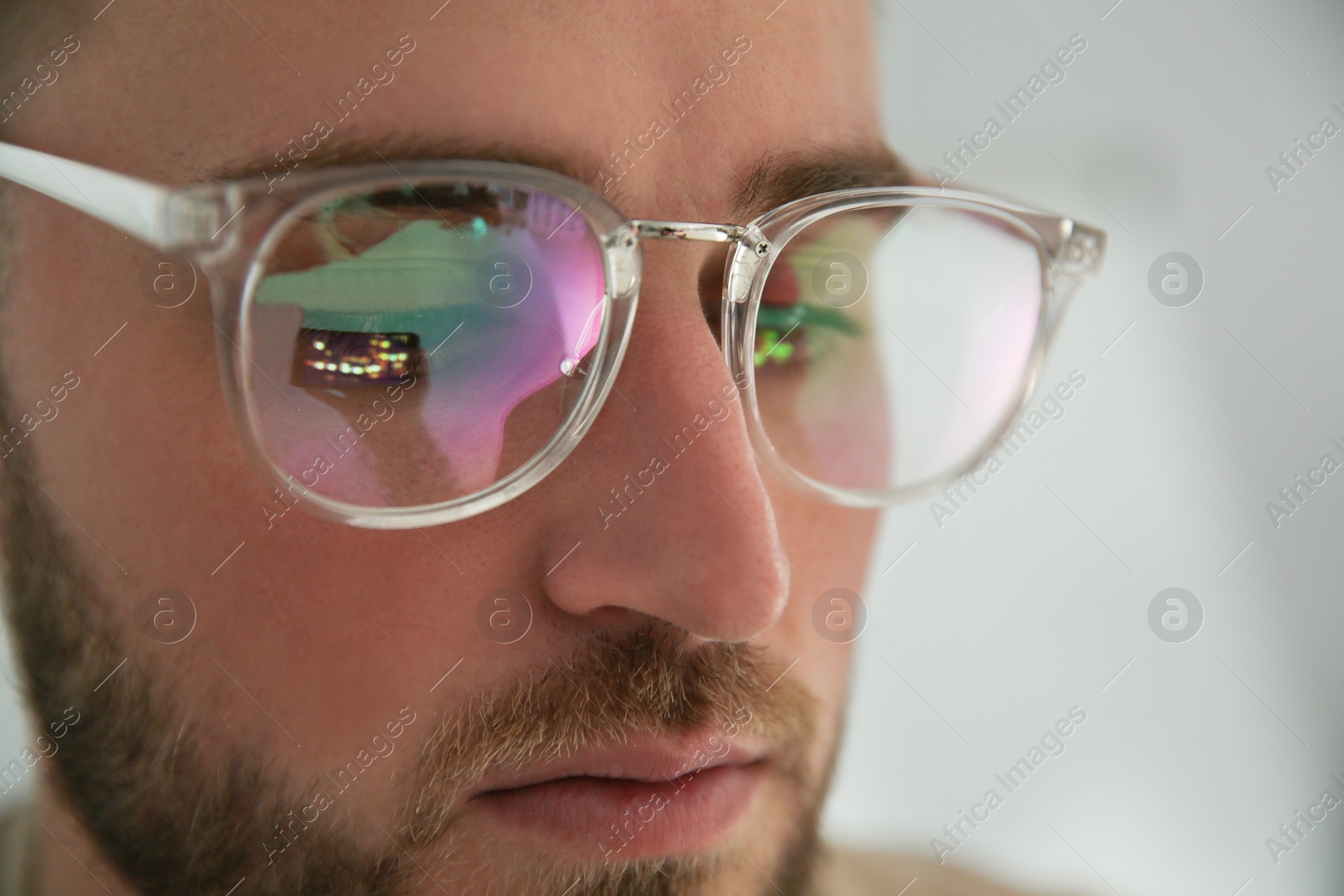 Photo of Young man wearing glasses on blurred background, closeup. Ophthalmology service