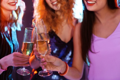 Young women chinking glasses in nightclub, closeup. Birthday party