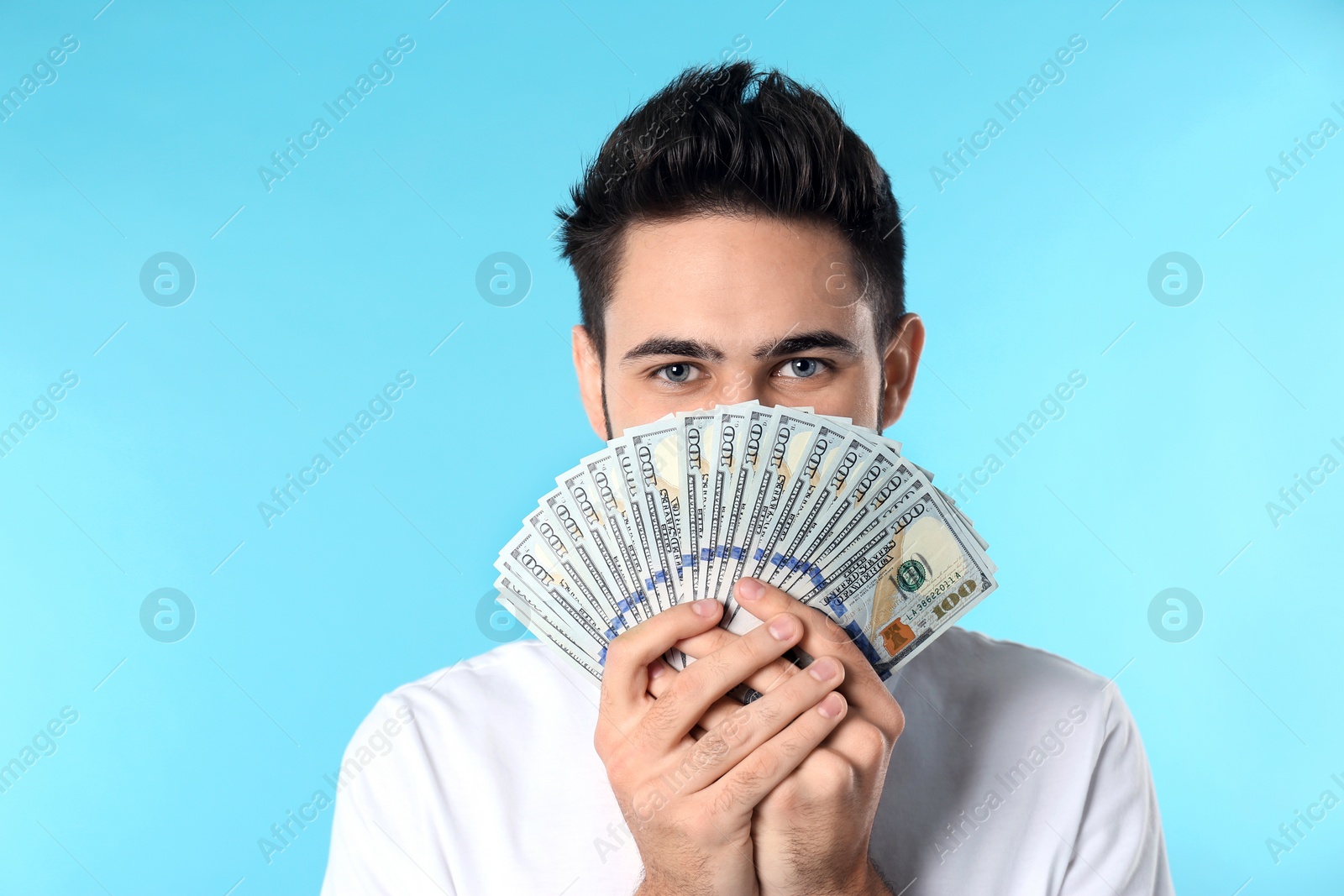 Photo of Portrait of happy young man with money on color background