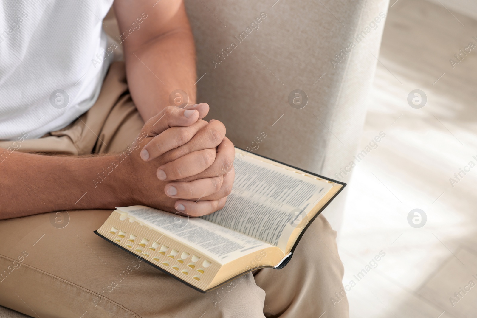 Photo of Religious man with Bible praying indoors, closeup